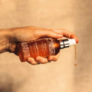 Pouring organic body oil showing lightweight texture