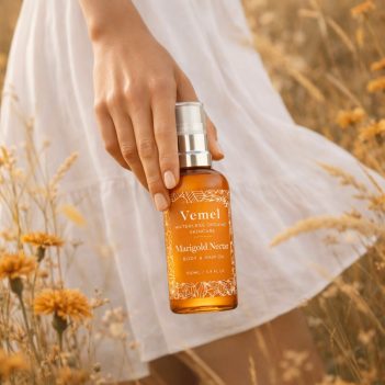 Vemel waterless organic Marigold Nectar body oil held in a meadow natural organic setting