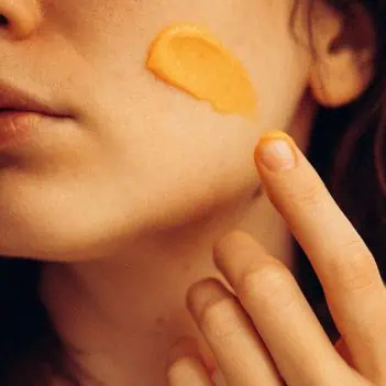 Applying vitamin rich face butter texture to skin for hydration