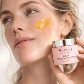 woman applying glow resurfacing mask on cheek